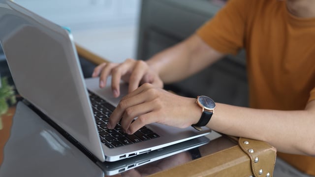 A Man Typing On A Laptop