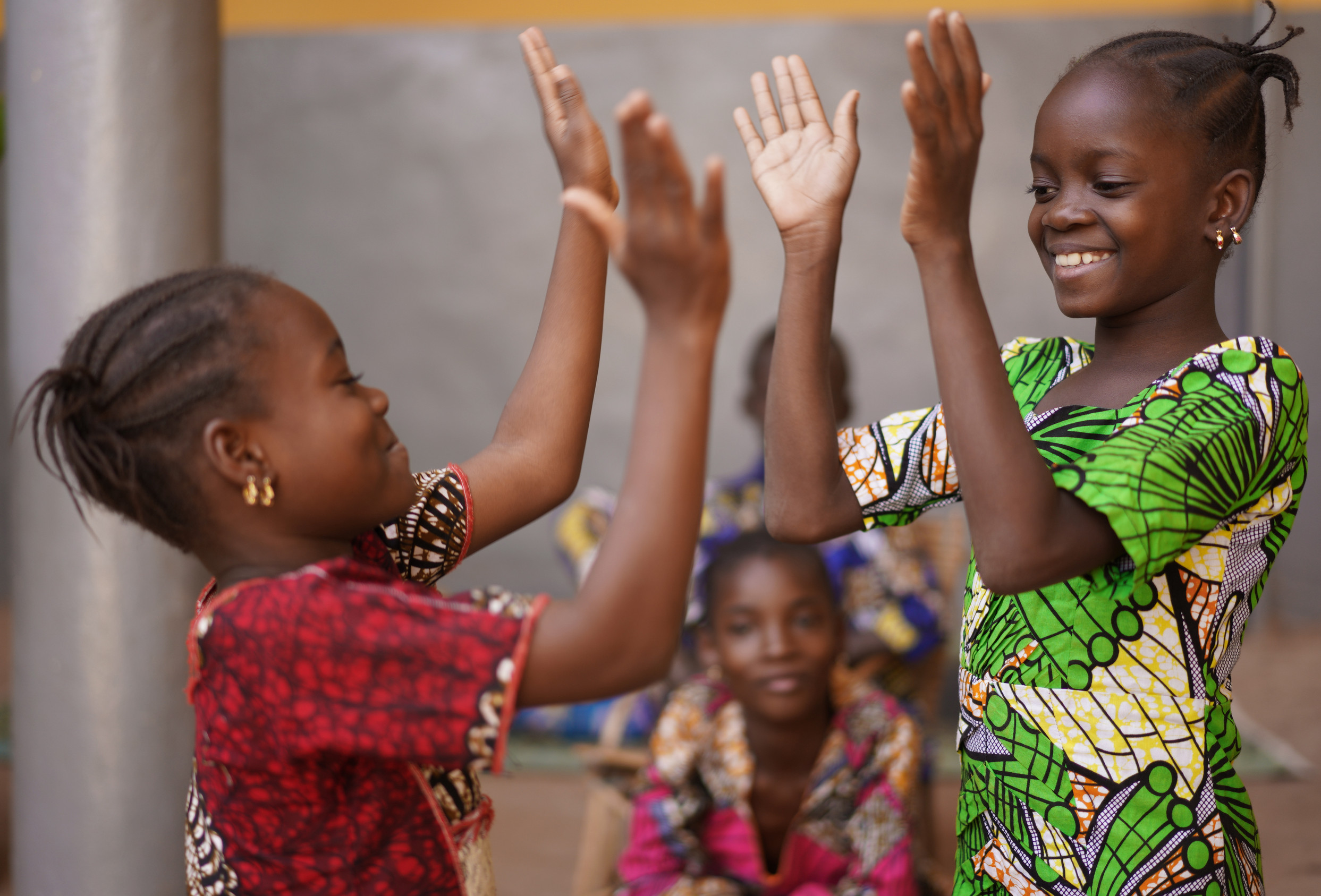 Two young African girls engaged in a hand clapping game