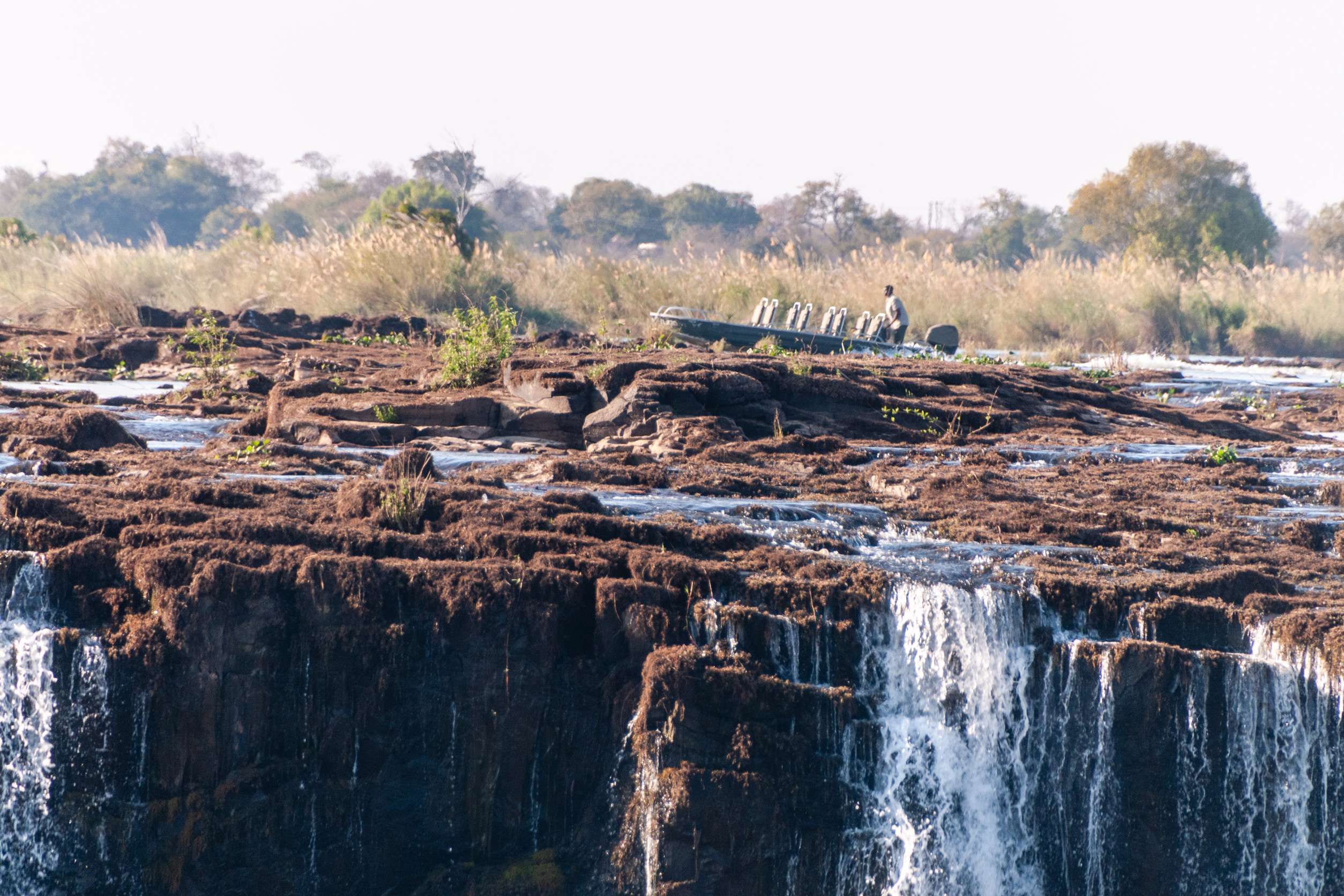 a tour boat is passing along the upper part of vic falls