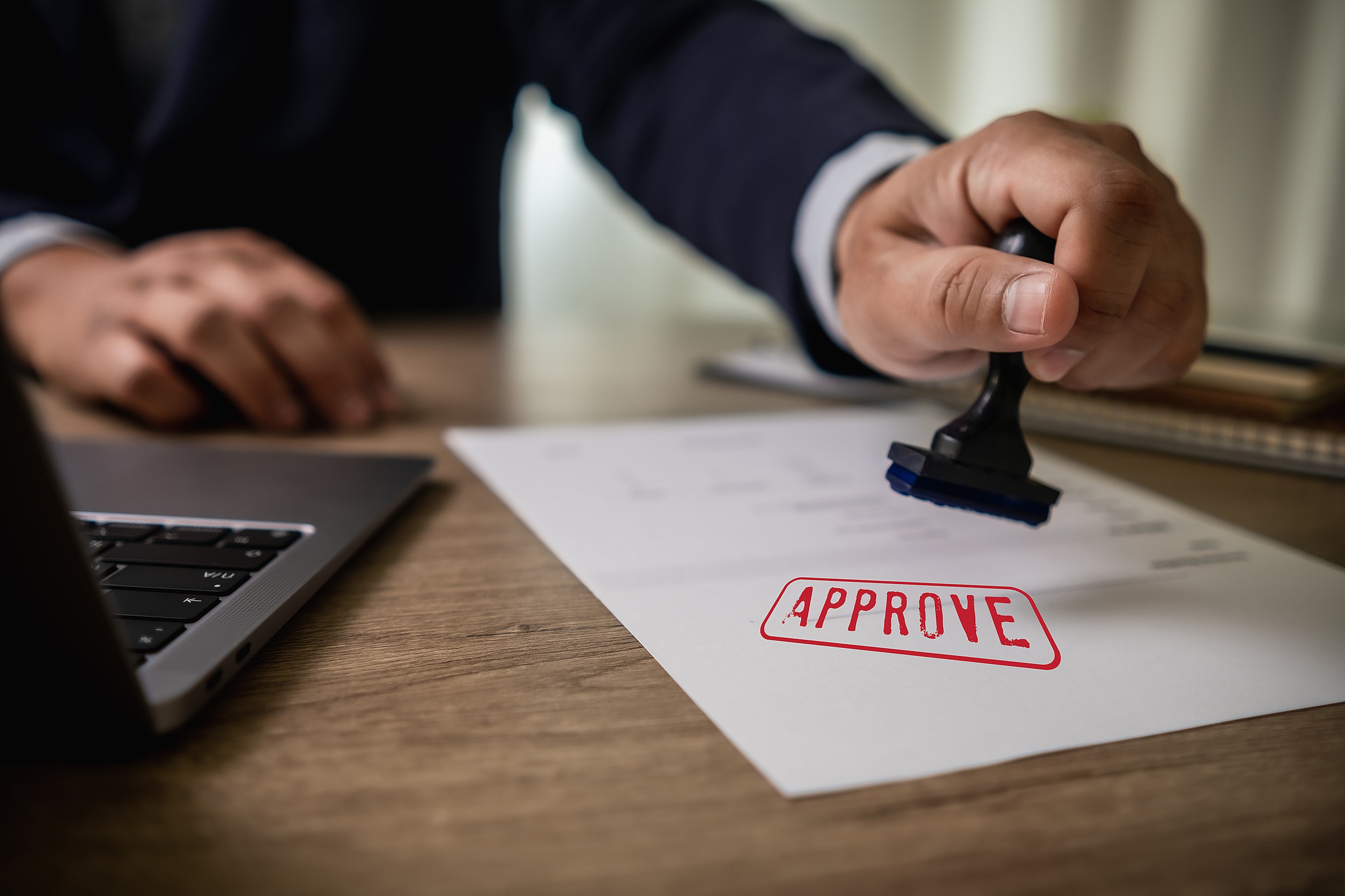 man stamping approval text is approved by stamping the document on paper